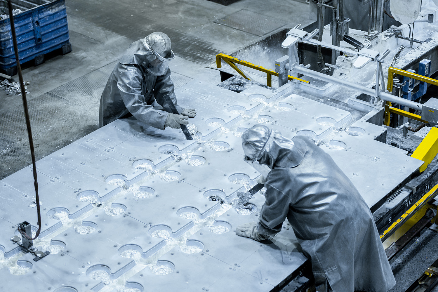 a couple people in protective gear working on a large piece of concrete