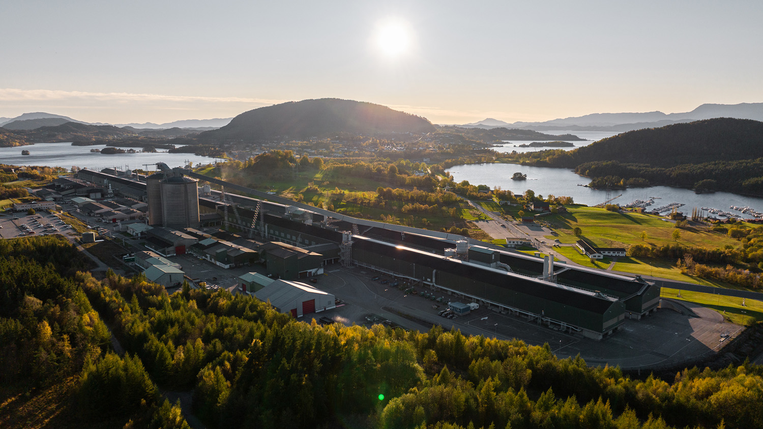 a large building with a parking lot and a body of water in the background